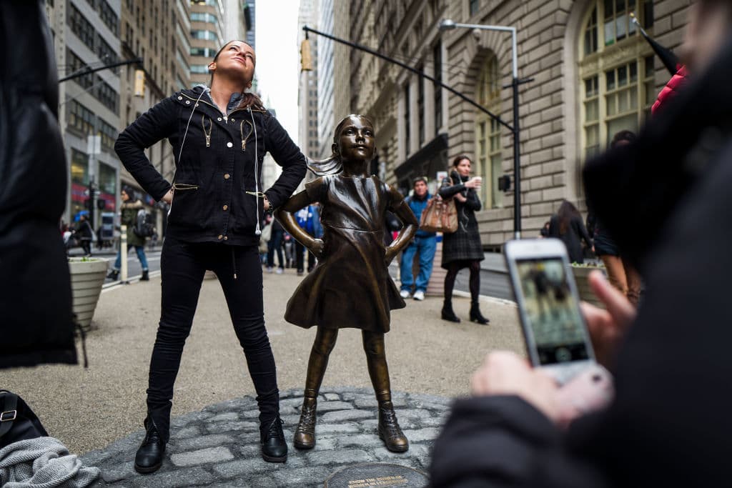Imitando la pose de la niña, una mujer posa junto a la estatua en
<b><a href="http://www.univision.com/noticias/trending/8-de-marzo-de-2017-el-dia-internacional-de-la-mujer-se-convierte-en-el-dia-sin-mujeres">el Día Internacional de la Mujer</a></b>. (Getty Images)