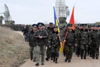 Militares ucranianos ondeaban dos grandes banderas, una ucraniana y una soviética, frente a soldados rusos.