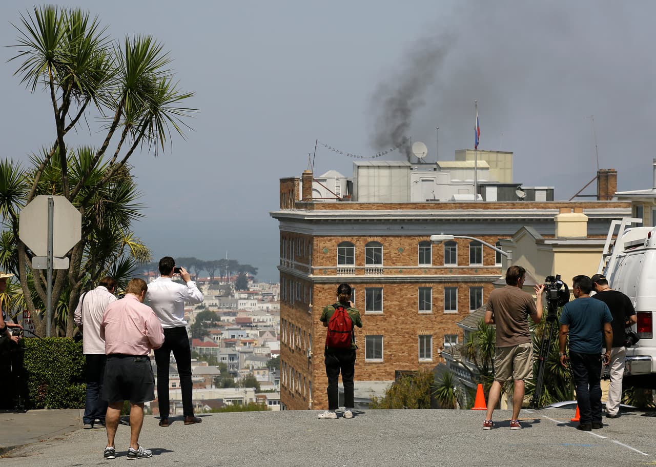 People stop to watch black smoke coming from the roof of the Consulate-General of Russia Friday, Sept. 1, 2017, in San Francisco. The San Francisco Fire Department says acrid, black smoke seen pouring from a chimney at the Russian consulate in San Francisco was apparently from a fire burning in a fireplace. The smoke was seen billowing from the consulate building a day after the Trump administration ordered its closure. (AP Photo/Eric Risberg)