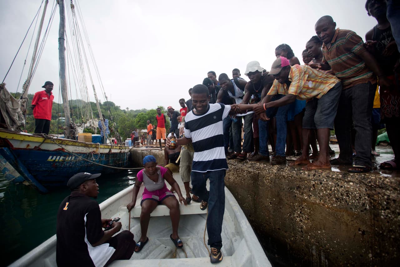Partidarios de Philippe le ayudan a subir a un bote tras un acto de campaña en Corail.
