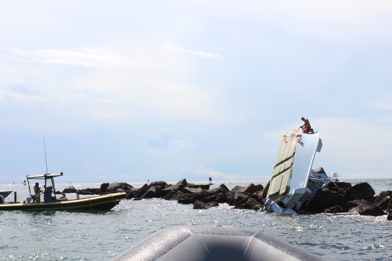 Official begin the investigation by towing the boat off the rocks.