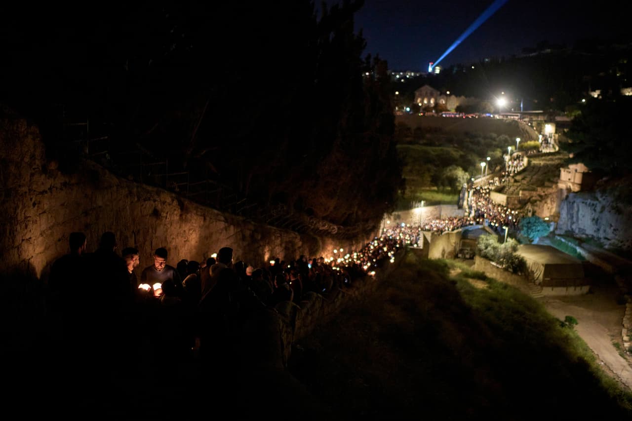 Fieles católicos sostienen velas mientras en una procesión por un camino
<b>que se cree fue recorrido cuando Jesús fue arrestado y llevado a juicio, </b>fuera de la Ciudad Vieja de Jerusalén.
<br>
<br>
<b>En este propósito lo acompaña el Patriarca Ecuménico Bartolomé, líder espiritual de los ortodoxos, quien ha calificado la iniciativa como un “verdadero paso hacia la reconciliación”. </b>La relación entre ambos líderes ha sido cercana, marcada por gestos simbólicos y declaraciones mutuas de respeto y hermandad.