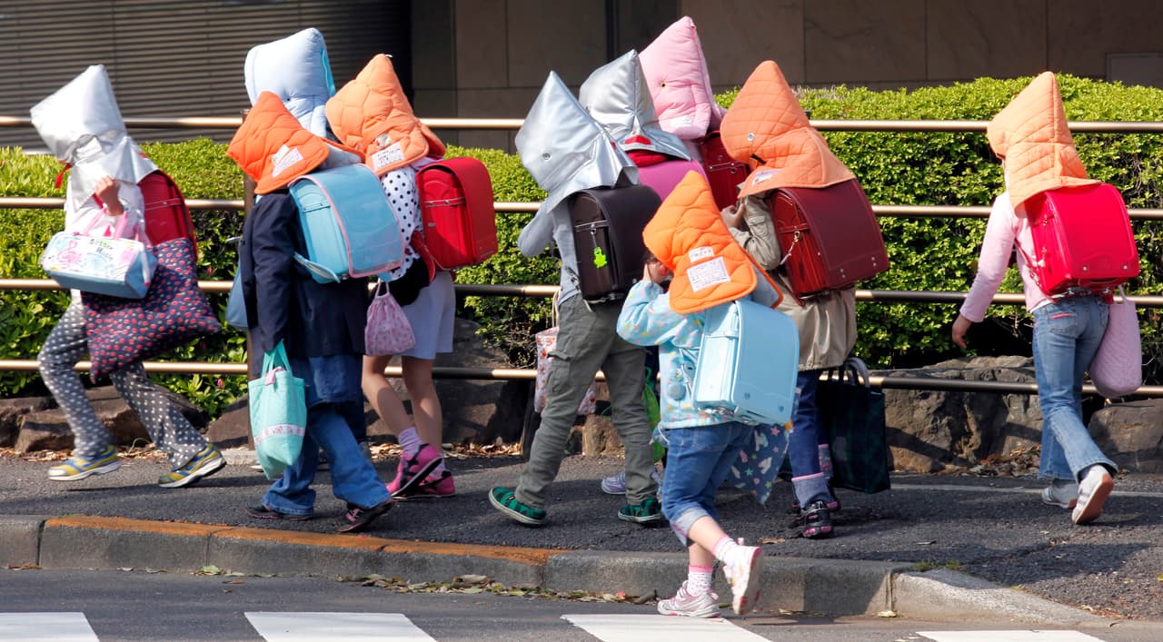 <b>Japón.</b> Estudiantes de primaria usan sombreros protectores de camino a su escuela en Tokio, un mes después de que un fuerte terremoto y tsunami golpeara al país. 25 de abril de 2011.