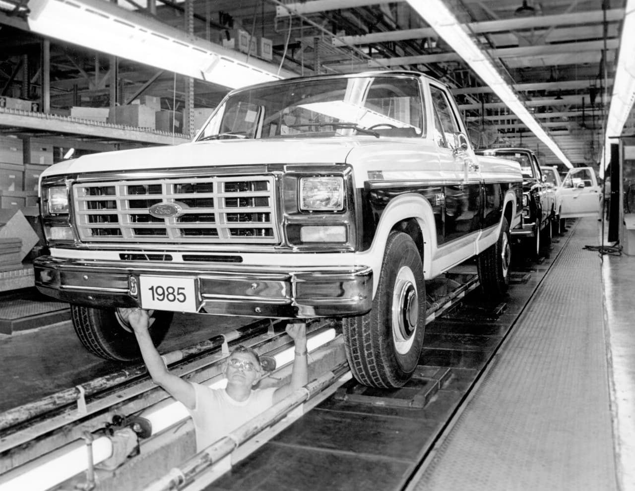 La 
<b>séptima generación</b> marcó varios hitos importantes en la historia de la Serie-F; 1983 fue el último año en que la F-100 se produjo mientras que 1986 fue el último año en que la Ford F-150 utilizó una transmisión manual de 3 velocidades con la palanca montada en la columna de la dirección. Igualmente vio la llegada de 
<b>avances tecnológicos hasta el momento reservados sólo para los automóviles de pasajeros</b> como vidrios, espejos y seguros accionados por mecanismos eléctricos. La modernidad llegó de golpe al mundo de las pickups. La imagen muestra una F-150 siendo construida en la planta de ensambla de St. Paul en Minnesota, la cual cerró sus puertas en 2011.