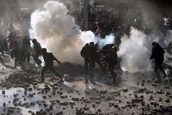 La policía ucraniana cercó hoy a los manifestantes en el corazón de las protestas opositoras de la plaza de la Independencia de Kiev (Maidán), tras una jornada en la que murieron 14 personas en los disturbios que estallaron en la capital. Víktor "Yanukóvich se ha convertido en un presidente sangriento", aseguró hoy el dirigente opositor Vitali Klitschkó en un llamamiento a los países democráticos para que intervengan en Ucrania y frenen la violenta confrontación. Según se acercaba la medianoche, los temidos Berkut, el destacamento antidisturbios, estrechaban el cerco en torno a los miles de manifestantes concentrados en el Euromaidán, bastión de las protestas desde el pasado 21 de noviembre. "Los extremistas de la oposición han cruzado la línea roja; matan a inocentes en la calles de la capital de Ucrania, vejan a mujeres, queman edificios y automóviles. Y si los disturbios continúan, nos veremos obligados a actuar con firmeza", rezaba el ultimátum del Servicio de Seguridad y el Ministerio del Interior de Ucrania. Advierten a los americanos que se queden dentro de las casas y de nuevo se sienten explosiones en la ciudad.