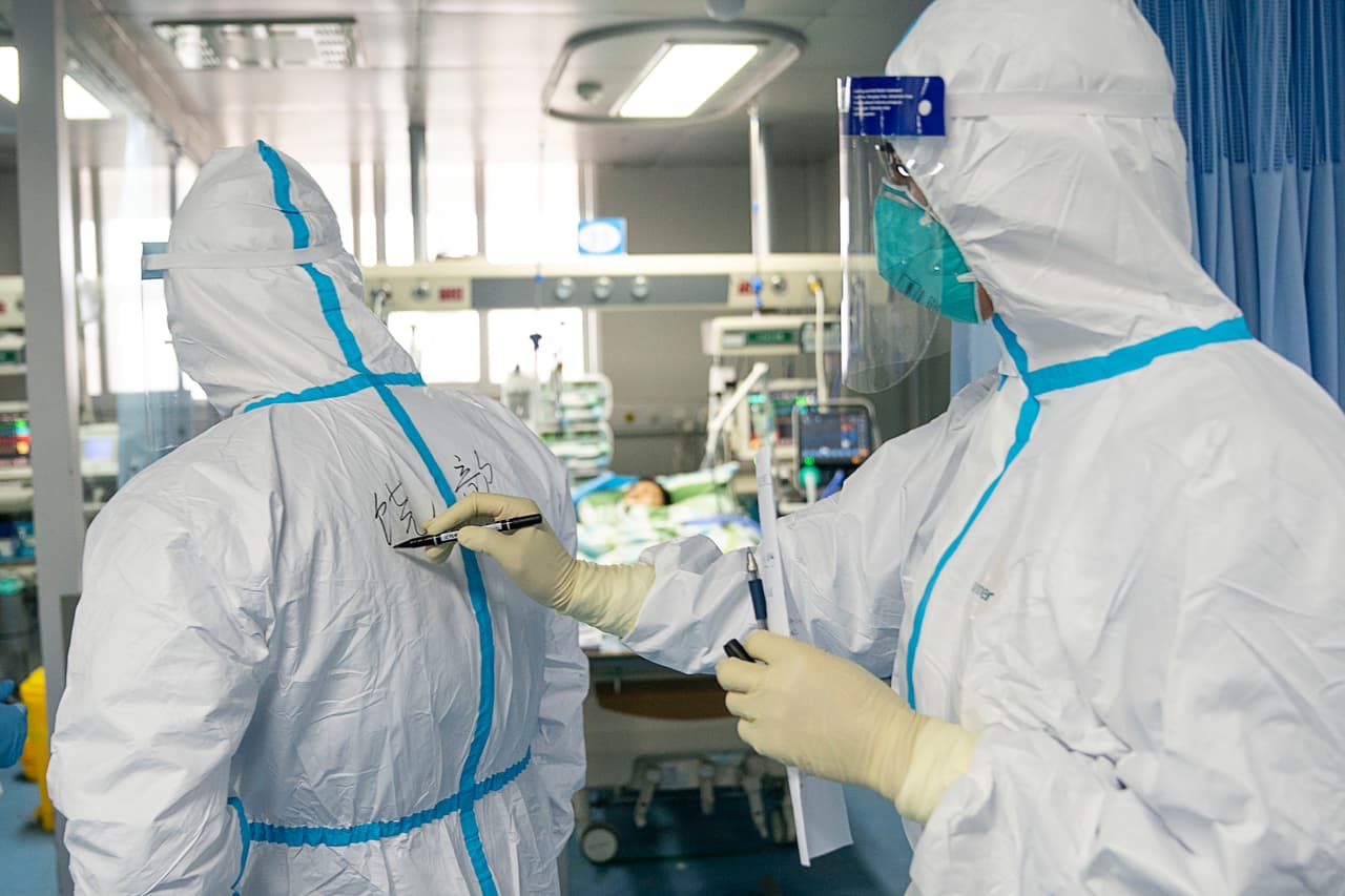 En esta foto publicada por la Agencia de Noticias Xinhua de China, el 24 de enero, un médico escribe el nombre de su colega en un traje de protección para ayudar en la identificación mientras trabajan en el Hospital Zhongnan, de la Universidad de Wuhan.