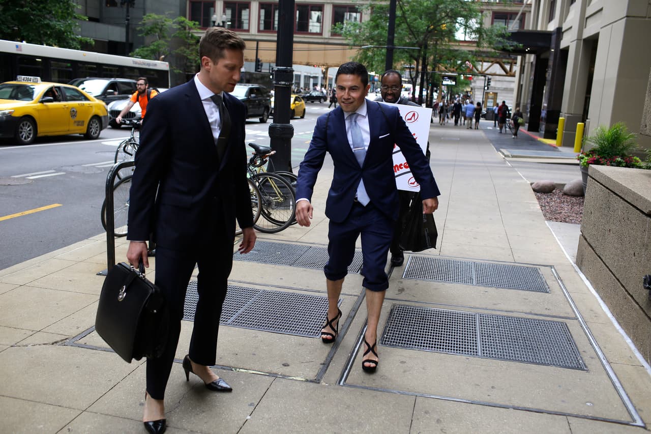 Los abogados Jonathan Mraunac observa a su colega Octavio Durán, quien trata de mantener el equilibrio mientras camina en zapatos de tacón alto.