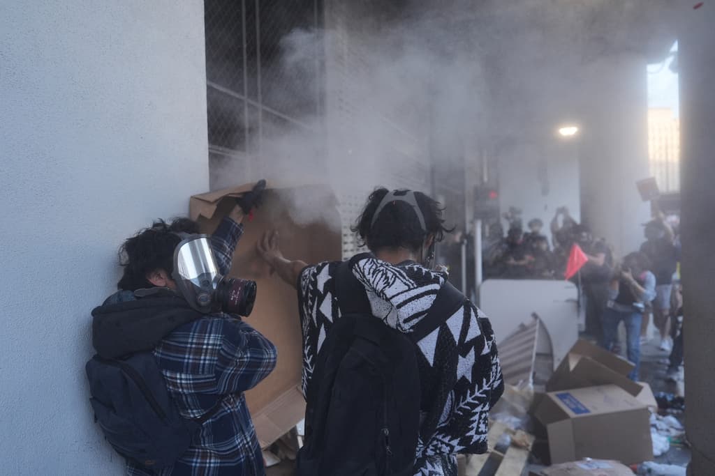 Manifestantes construyen una barricada a lo largo del muelle de carga mientras la policía federal dispara gases lacrimógenos en el Centro de Detención Metropolitano en el centro de Los Ángeles.