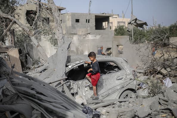 Un niño palestino mira entre los escombros de una casa y un auto destruidos por un ataque israelí en Gaza.