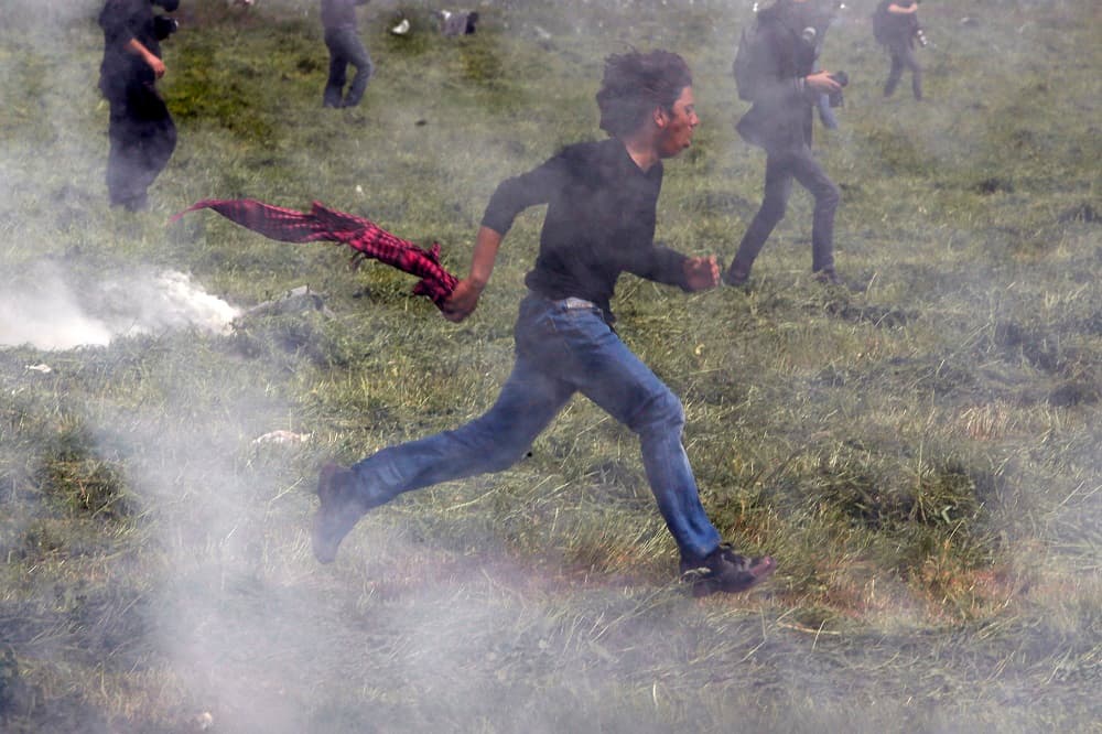 Un inmigrante corre después de que agentes respondieran al intento de un grupo de 30 personas de saltar de Grecia a Macedonia.