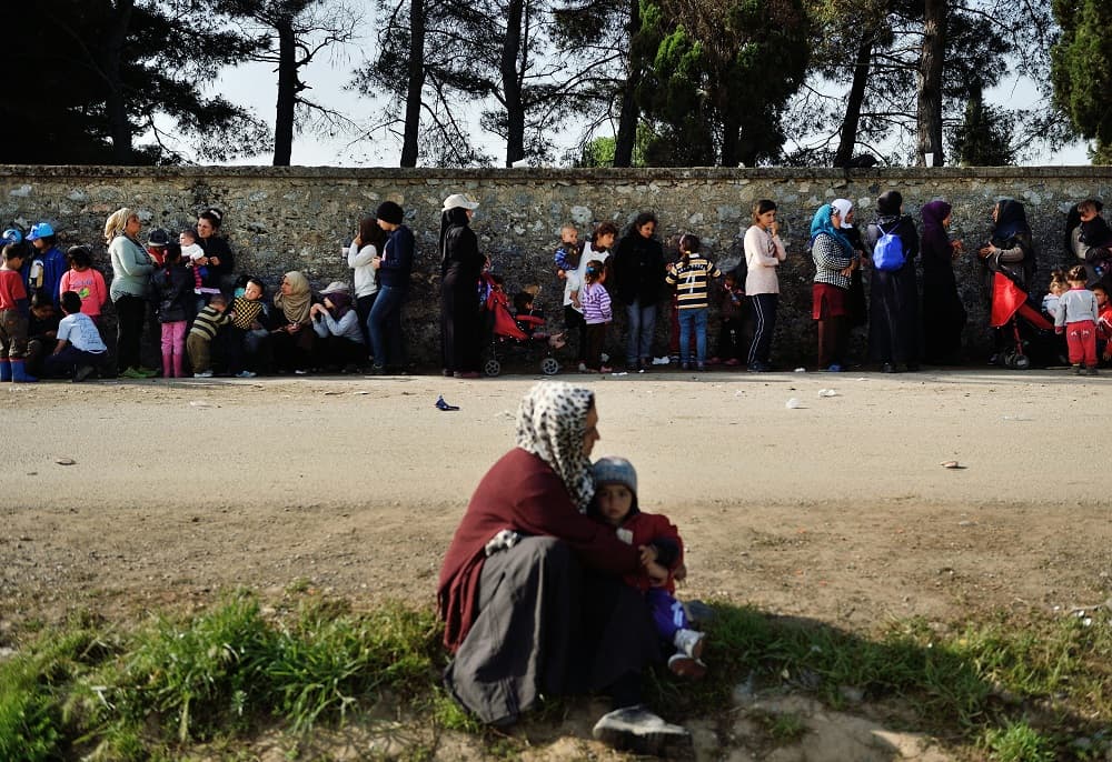 Una fila de refugiados espera en el paso de la frontera para poder tener comida.