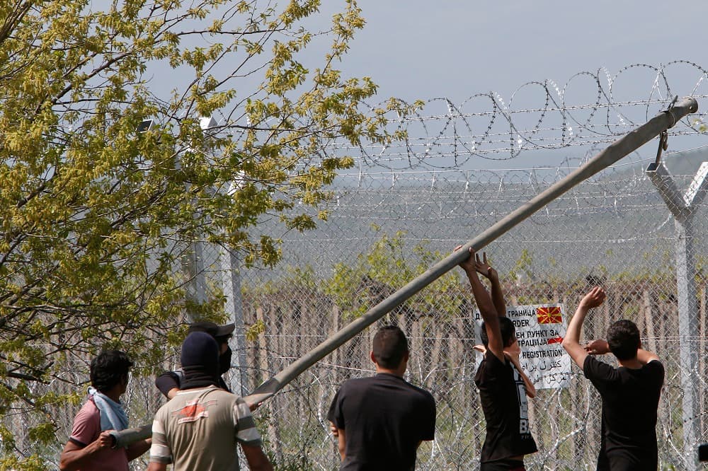 Un grupo de seis migrantes tratan de tirar abajo el "muro" alambrado que separa a los dos países.