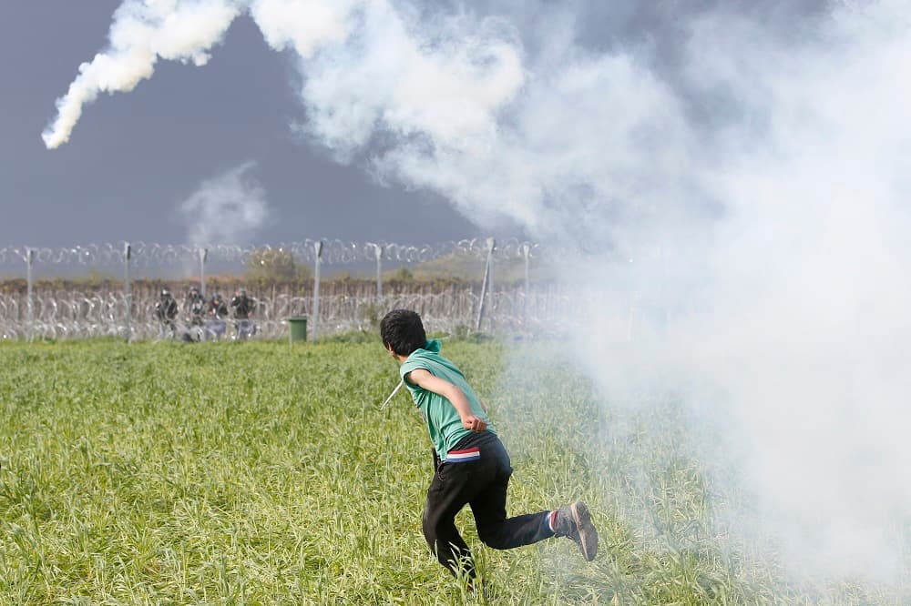 Un inmigrante devuelve una de las granadas lacrimógenas desde el lado griego a las fuerzas de Macedonia.