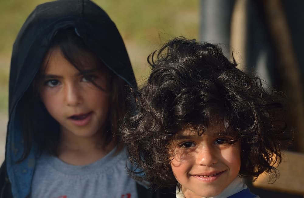 Dos niños refugiados en el paso de Idomeni mientras esperan junto a sus familiares para poder conseguir algo para comer.