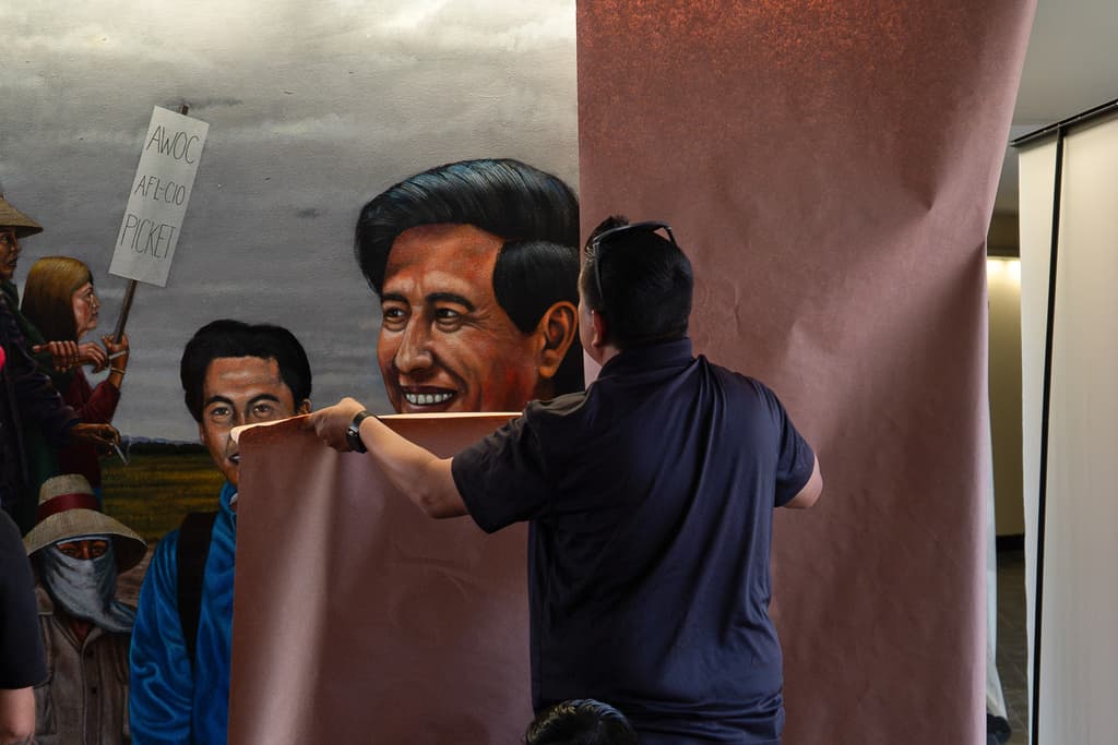 Un trabajador cubre un mural pintado por Emigdio Vásquez que representa a César Chávez, en el Santa Ana College de Santa Ana, California, el jueves 19 de marzo de 2026.