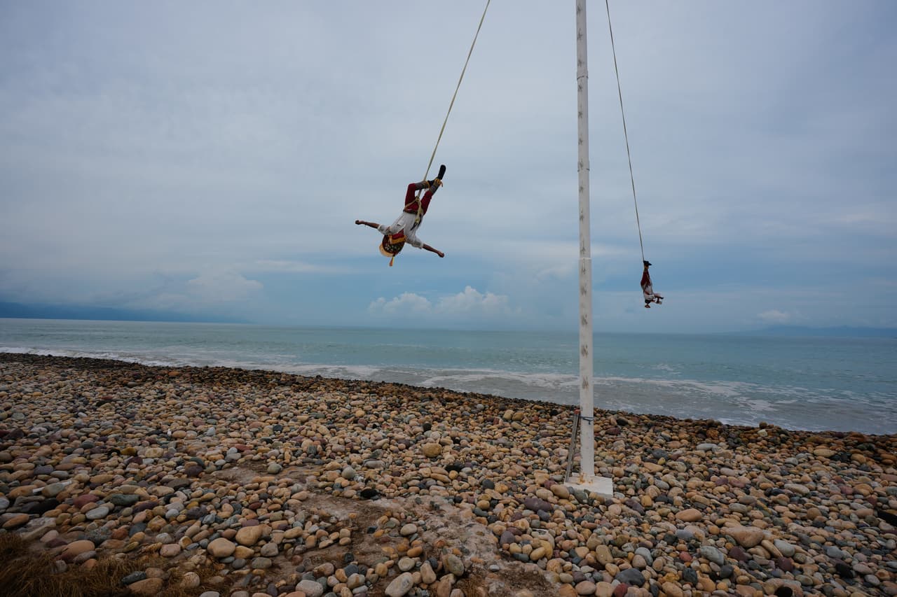 Los Voladores de Papantla interpretan la "Danza de los Voladores" en la playa mientras el huracán Simón se acerca a Puerto Vallarta, México.