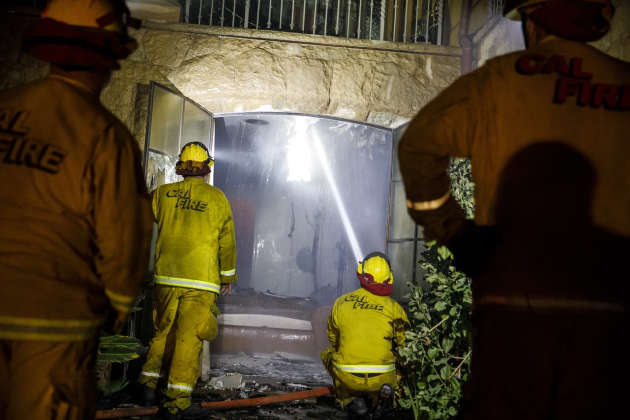 Los bomberos del condado Humboldt, en Montecito, California, lanzan agua por uno de los ventanales de la casa.