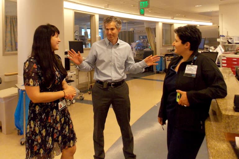 La neonatóloga Joanna Parga, el cardiólogo pediatra Mark Sklansky y la enfermera Anahit Sarin-Gulian hablan de la zona de apretón de manos mientras permanecen en la unidad de cuidados intensivos neonatales del Centro Médico Ronald Reagan UCLA.