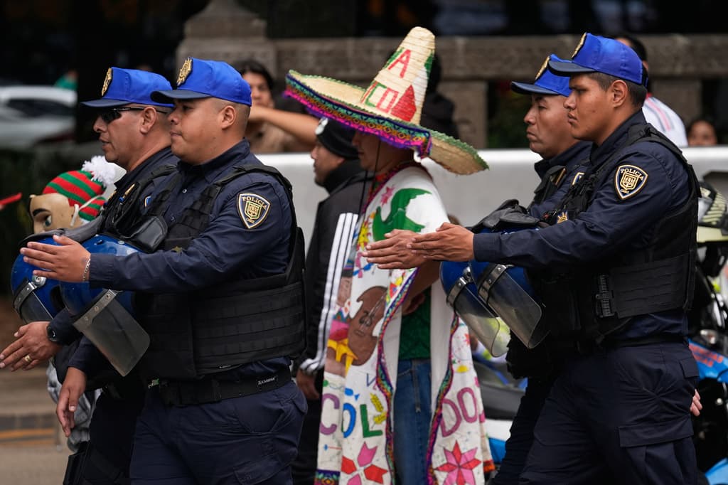Una fila de policías marcha frente a aficionados al fútbol durante una reunión para ver el partido de la Copa del Mundo.