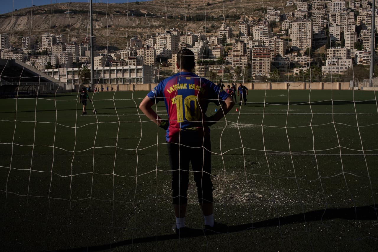 Un joven palestino de una academia de fútbol local, vestido con una camiseta del Barcelona que lleva el nombre del futbolista español Lamine Yamal, participa en una sesión de entrenamiento en el estadio municipal de Nablus, ciudad de Cisjordania, el jueves 7 de mayo de 2026. (Foto AP/Leo Correa)