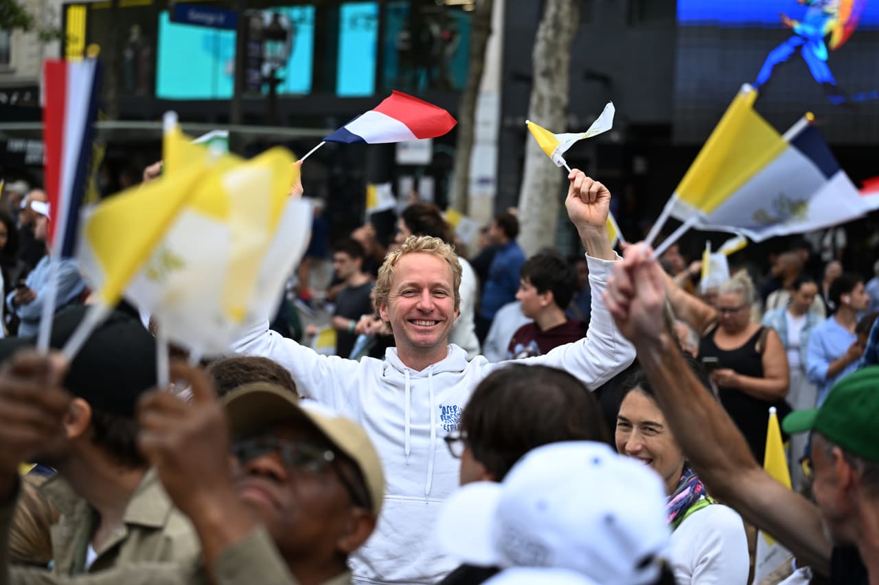 Varias personas esperan al Papa León XIV en la avenida de los Campos Elíseos antes de una misa en la Plaza de la Concordia en París, el sábado 26 de septiembre de 2026.