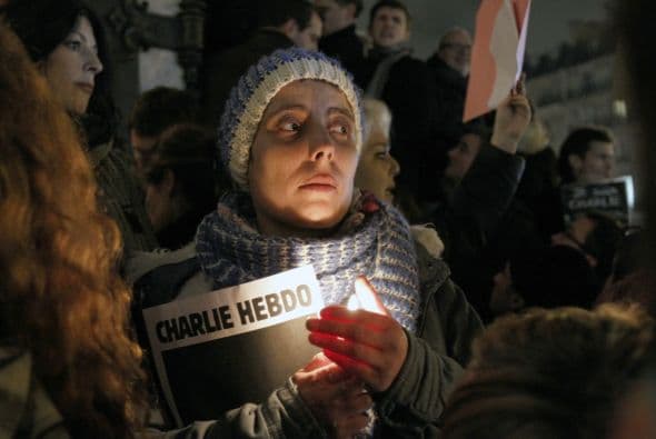 Una mujer sostiene una imagen de uno de los semanarios de Charlie Hebdo con la portada en negro, a manera de luto.