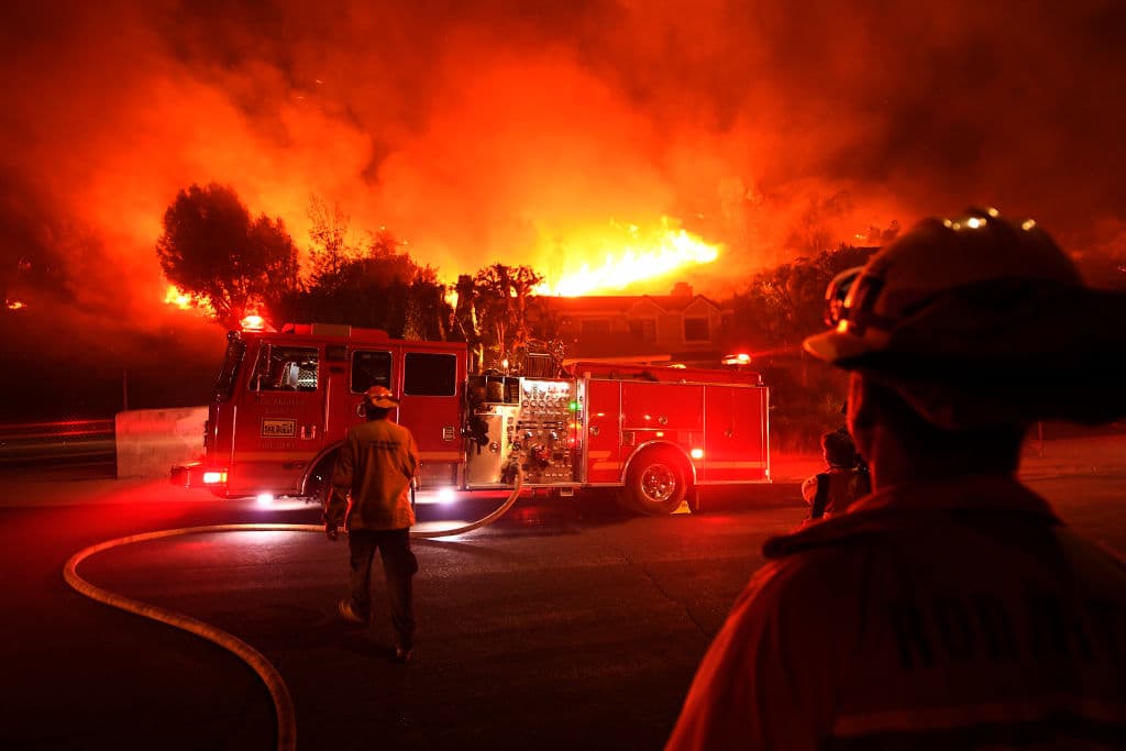 Los bomberos observan cómo el incendio forestal Woolsey arde detrás de una casa en el vecindario de West Hills en Los Ángeles, California. Kevork Djansezian/Getty Images