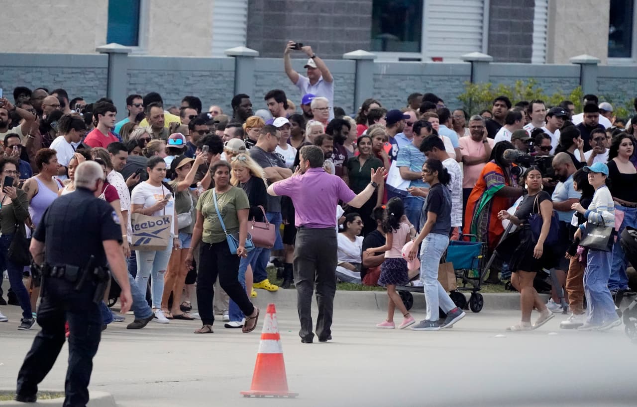 Un grupo de personas se reúne frente a una de las fachadas del centro comercial Allen Premium Outlets después de un tiroteo ocurrido el sábado 6 de mayo de 2023 en Allen, Texas.