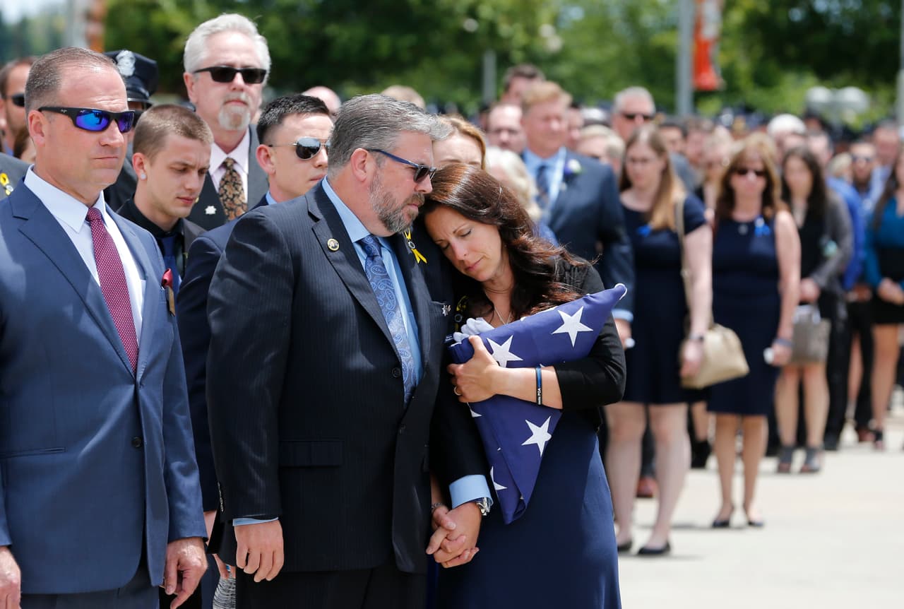 Kelley O'Sullivan se inclina hacia su esposo Denis mientras lleva en sus manos la bandera estadounidense que cubría el ataúd de su hija, la oficial Tara O'Sullivan de la Policía de Sacramento, durante sus servicios fúnebres en la iglesia Bayside Adventure en Roseville, California el 27 de junio.