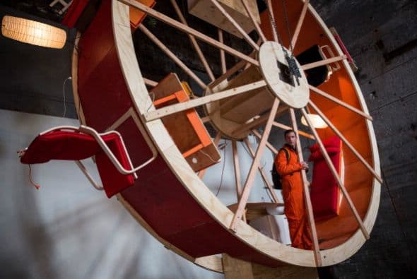 Hay veces que la monotonía de la vida se siente como una rueda de hámster gigante. De eso se trata el último performance de los artistas Ward Shelley y Alex Schweder de Brooklyn, quienes crearon una rueda de hámster de tres pisos en la que tendrán que coordinar cada movimiento durante 10 días. El performance llamado "En "rbita", está ubicado en una antigua sala de calderas en Williamsburg. Durante el performance, Schweder y Shelley van a comer, dormir, trabajar, ir al baño, etc, sin bajar de la rueda.