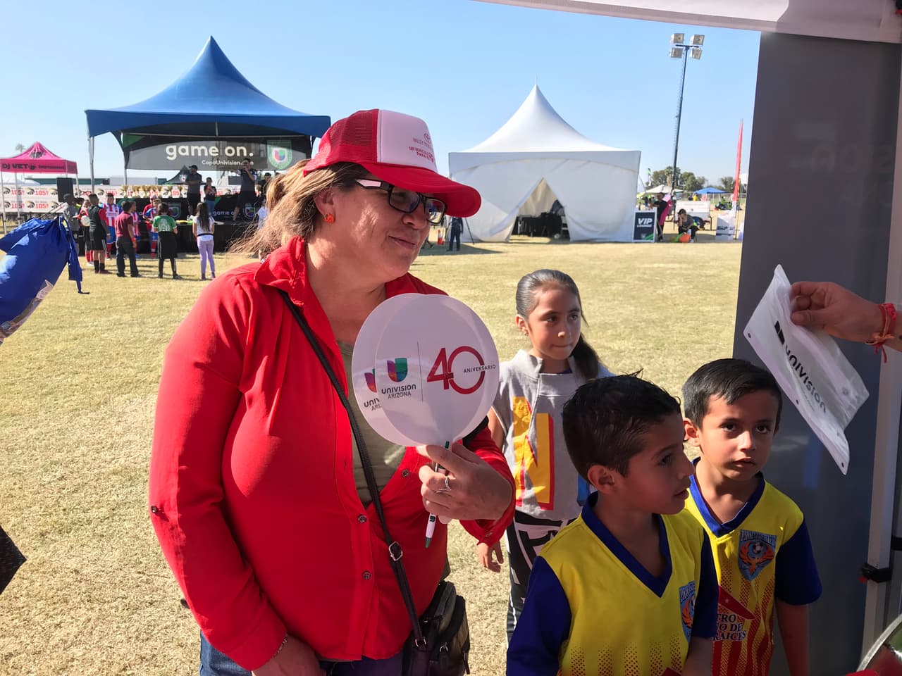 Señora muestra su abanico y su gorra de Univisión. 
<br>
