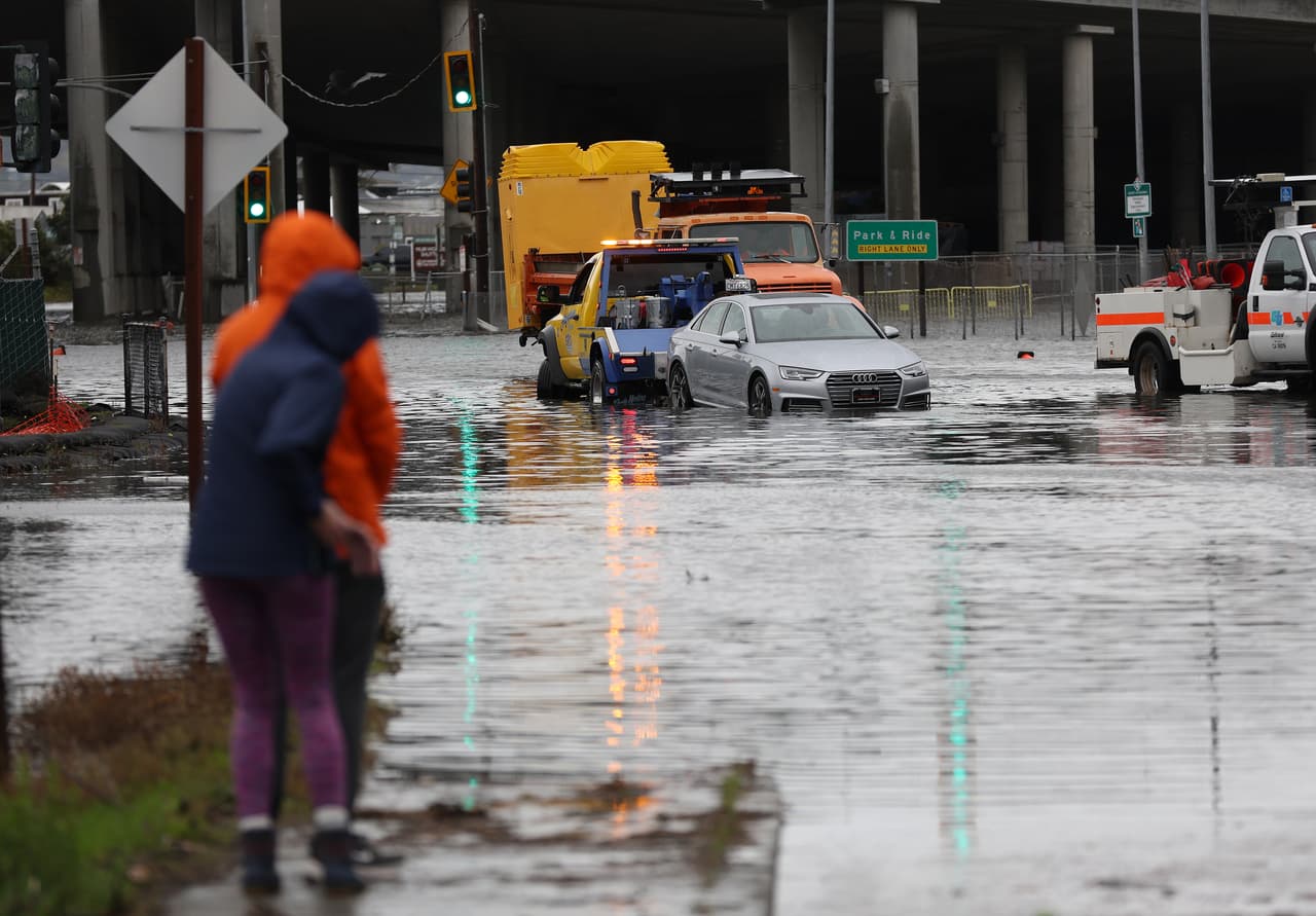 Decenas de intersecciones a lo largo y ancho del Área de la Bahía han quedado inundadas por las lluvias torrenciales. En la imagen, un par de peatones mira cómo una grúa saca un vehículo de una zona anegada en Mill Valley.