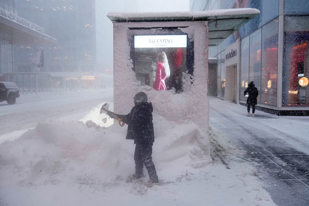 Un hombre palea nieve alrededor de un quiosco durante la tormenta invernal.