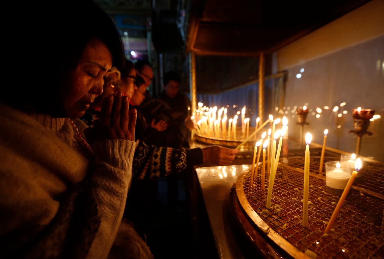 Un adorador cristiano reza después de encender una vela en la iglesia de la Natividad.