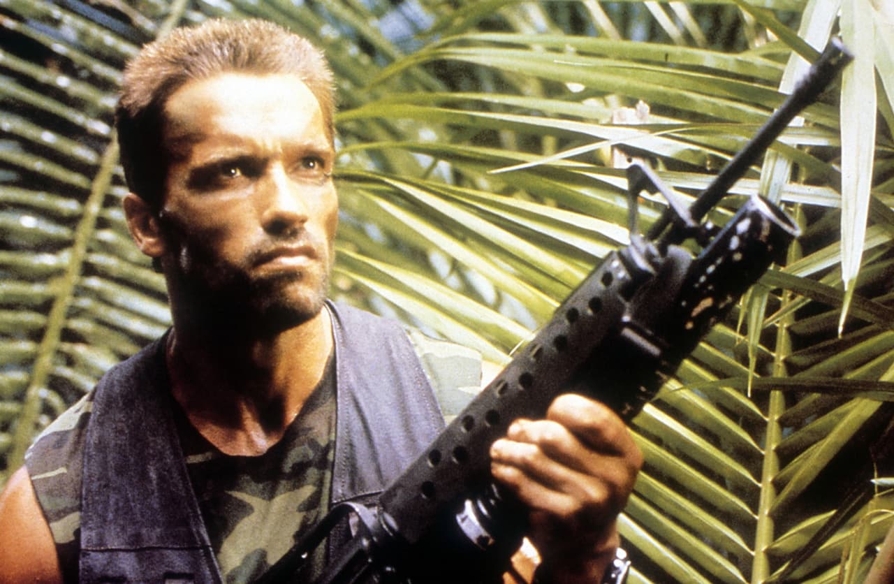 <b>Arnold Schwarzenegger</b>
<br>El mayor Alan "Dutch" Schaefer es el líder del grupo de mercenarios de elite que la CIA contrata, de forma clandestina, para rescatar a unos pilotos que son rehenes de una milicia en Guatemala. En la misión, Dutch y su equipo se topan con un extraterrestre que los caza uno por uno en la selva.