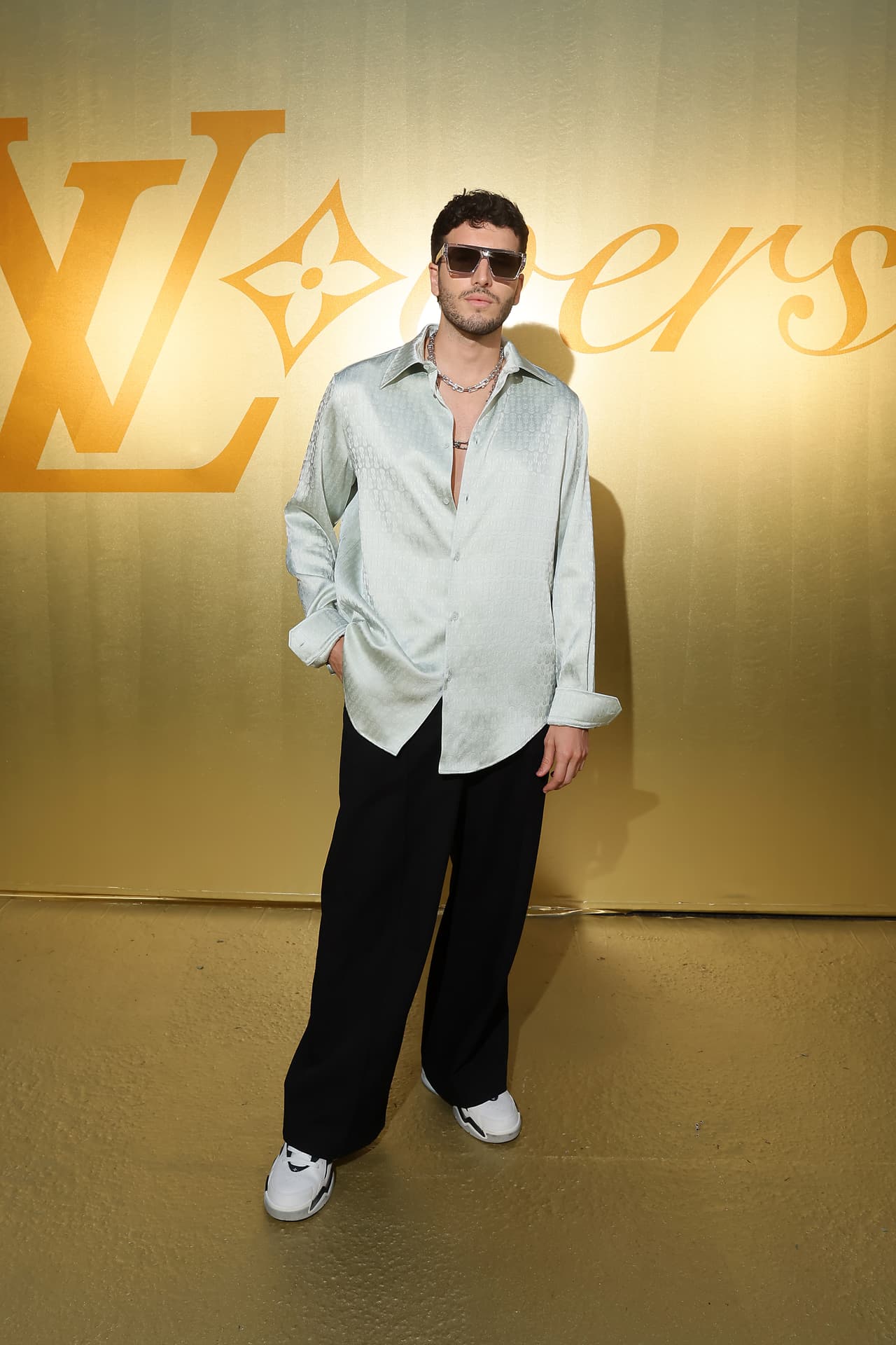 Sebastián Yatra apareció con un look sencillo pero brillante, con una camisa gris con grabados de guitarras, pantalones negros y anchos, y unos tenis blancos de la marca Louis Vuitton.