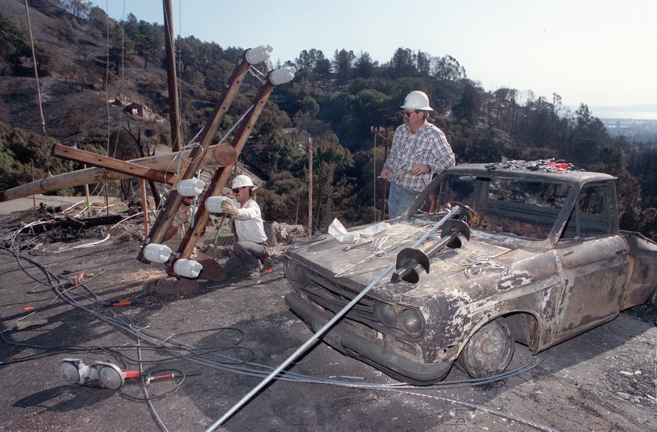 Los trabajadores de Pacific Gas & Electric intentan restablecer el orden en las líneas eléctricas en Oakland Hills, California, el miércoles 23 de octubre de 1991. 
<br>
<br>Miles de clientes de electricidad siguen sin electricidad en Oakland Hills debido a las líneas eléctricas destruidas en el incendio.