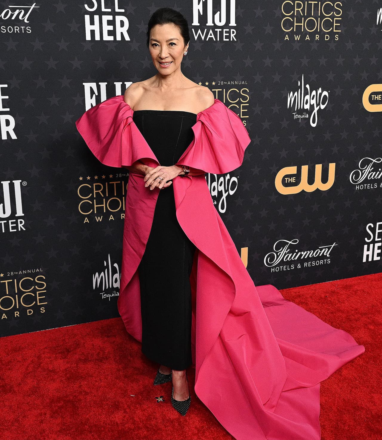 La actriz Michelle Yeoh lució un vestido negro sin tirantes Carolina Herrera, así como una capa rosa con volantes como mangas y una larga cola. Para completar su 'outfit', llevó unos tacones Jimmy Choo. 
<br>