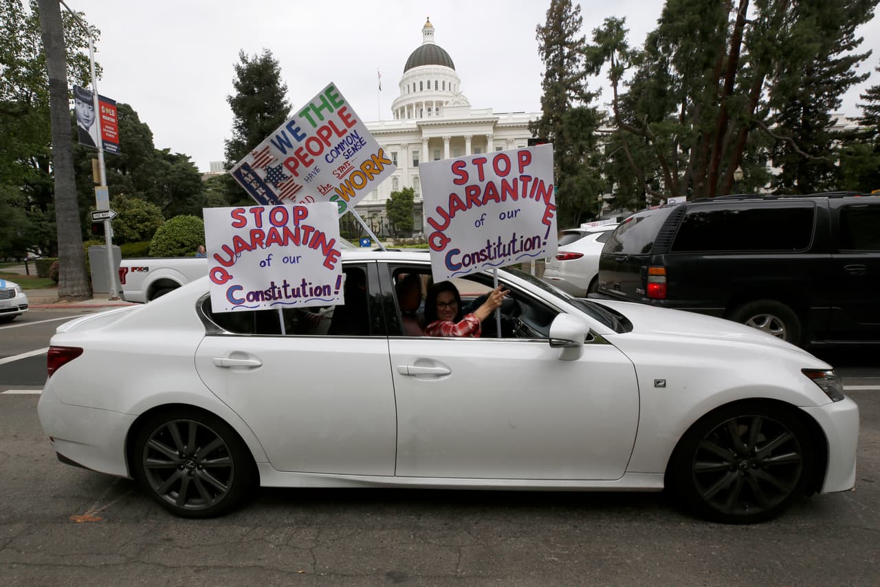 Decenas de autos manejaron alrededor del Capitolio, sonando el claxon y sosteniendo carteles que piden el fin de la cuarentena en California. (AP/Rich Pedroncelli)