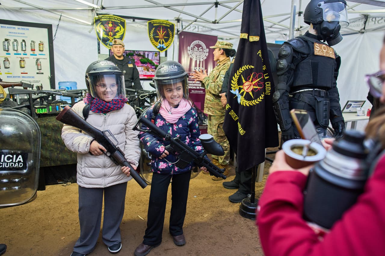 Juana Villano, a la derecha, y su hermana Francesca posan para las fotos en un puesto policial durante una feria de caza, pesca y actividades al aire libre en Buenos Aires, Argentina, el viernes 14 de agosto de 2026.