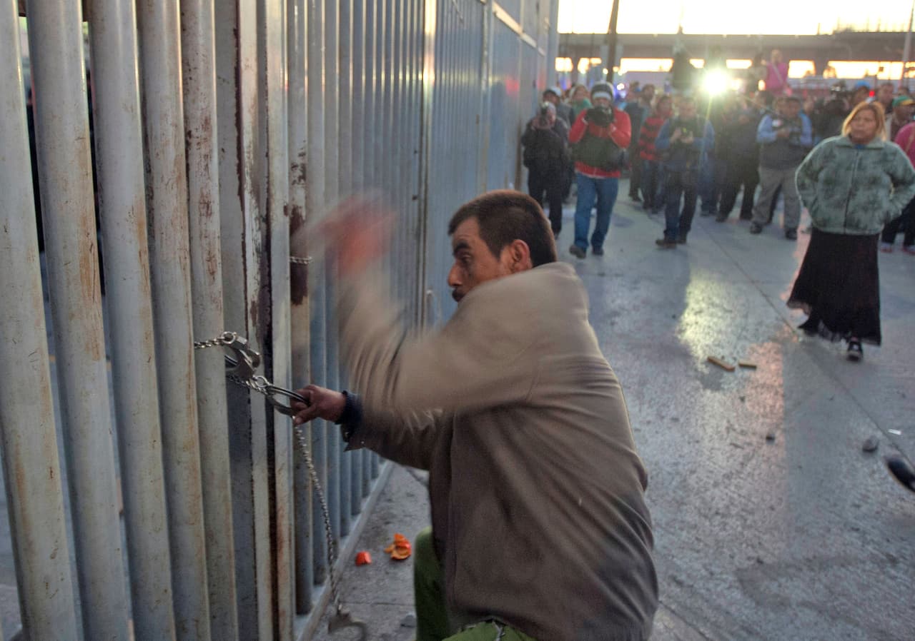 Uno de los familiares intenta romper una de las cadenas para entrar al penal.