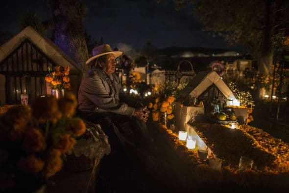Un hombre descansa junto a una tumba en Tzintzuntzan, Michoacán, donde es tradición hacer compañía a los familiares fallecidos en la noche del Día de Muertos.