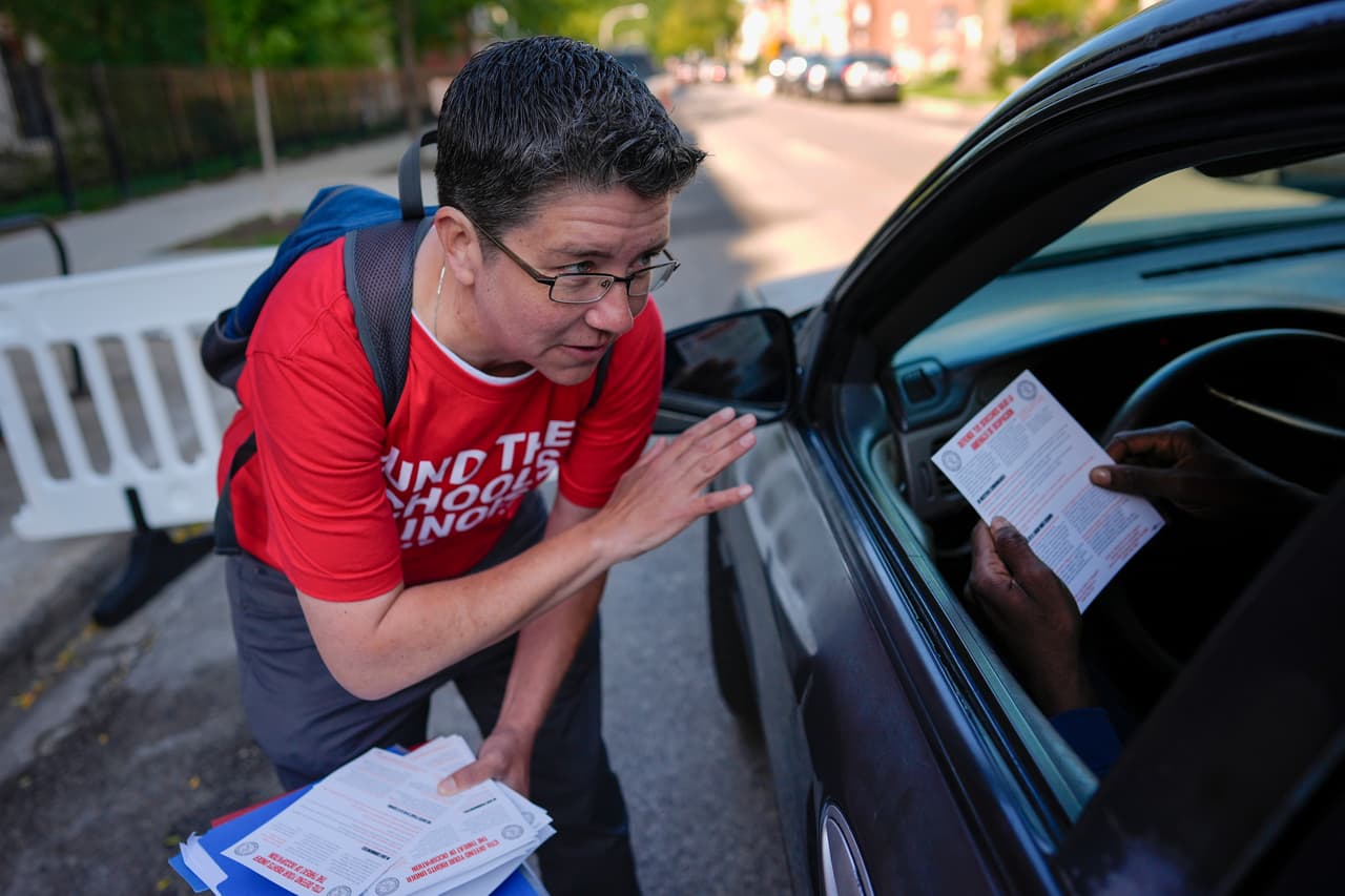Abbie Illenberger entrega un volante que dice:
<b> "Defiente tus derechos ante el riesgo de invasión"</b> a una persona que deja a sus hijos sin bajar del auto en la escuela Nash Elementary School.