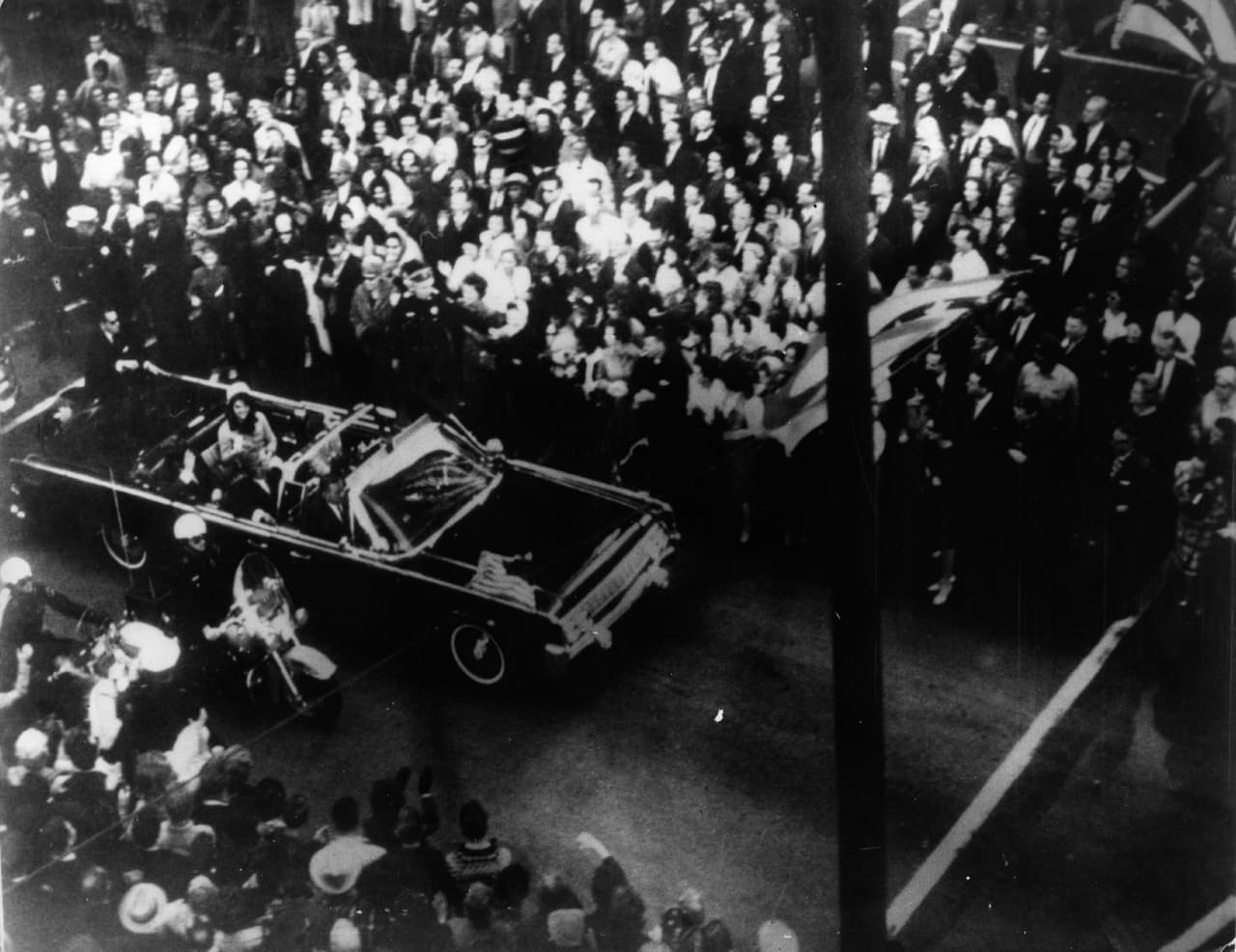 Esta fotografía fue tomada minutos antes del asesinato de John F Kennedy, se observa que va en el auto con la primera dama Jacqueline Kennedy en Dallas, Texas.
