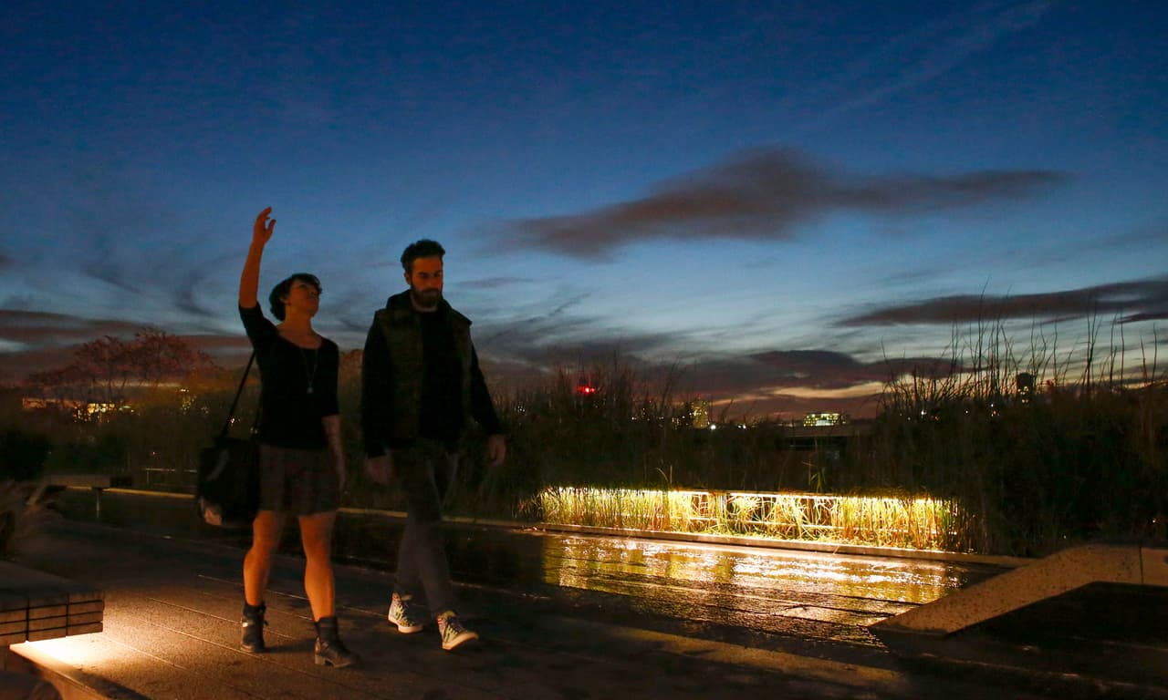 NEW YORK, NY - OCTOBER 24: A couple walks on the High Line during sunset on October 24, 2014 in New York City. Dr. Craig Spencer, who returned to New York from Guinea 10 days ago, tested positive for Ebola on October 23 and is now being cared for at Bellevue Hospital. Spencer, a member of Doctors Without Borders, visited the Blue Bottle Coffee stand located on the High Line after returning home. (Photo by Kena Betancur/Getty Images)