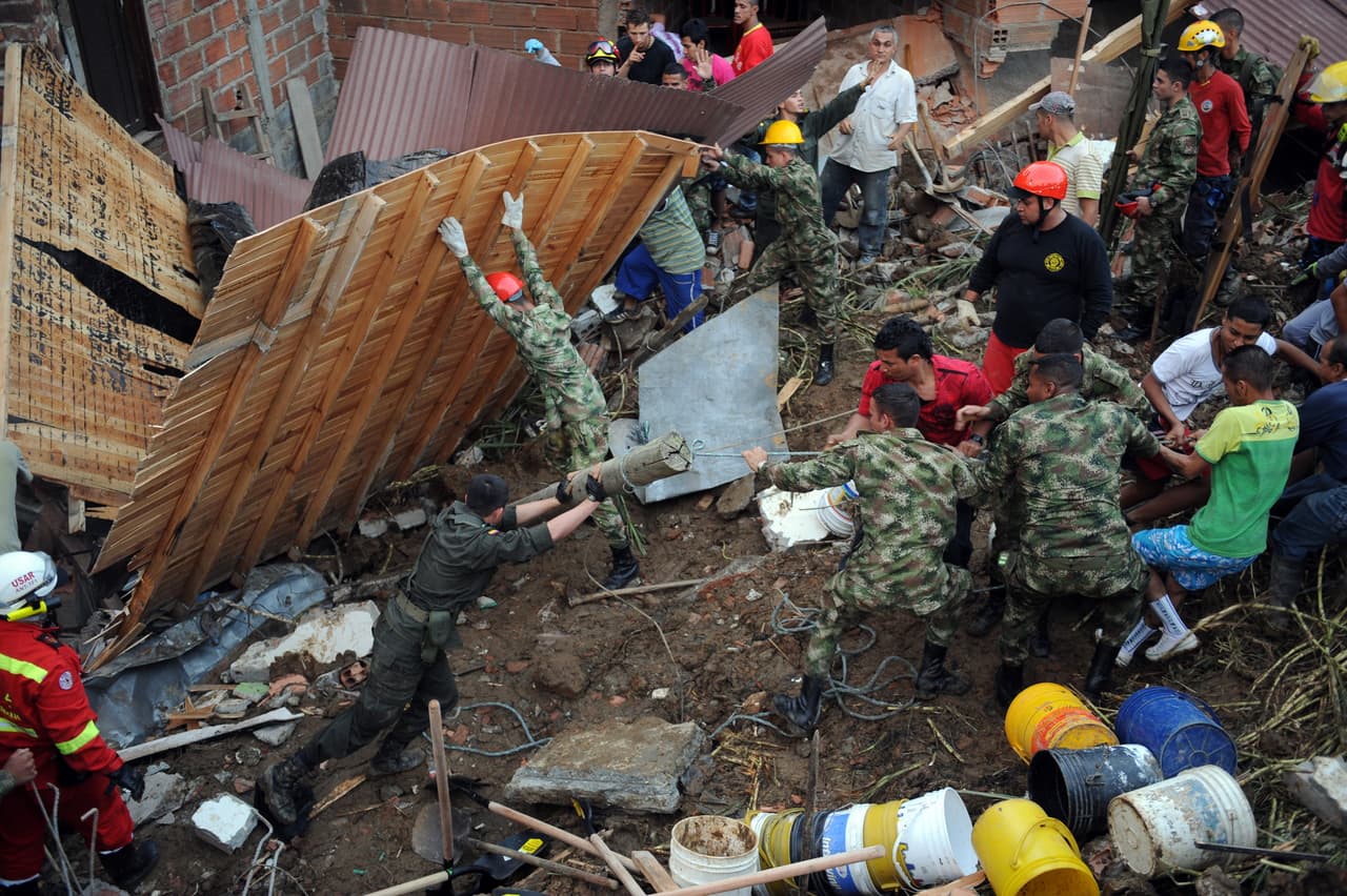 El 5 de diciembre de 2010, un deslizamiento de tierras en las afueras de Medellín, departamento de Antioquia en Colombia, dejó 45 muertos y un centenar de desaparecidos. Aquí se ven soldados junto a policías y bomberos tratando de remover los escombros.