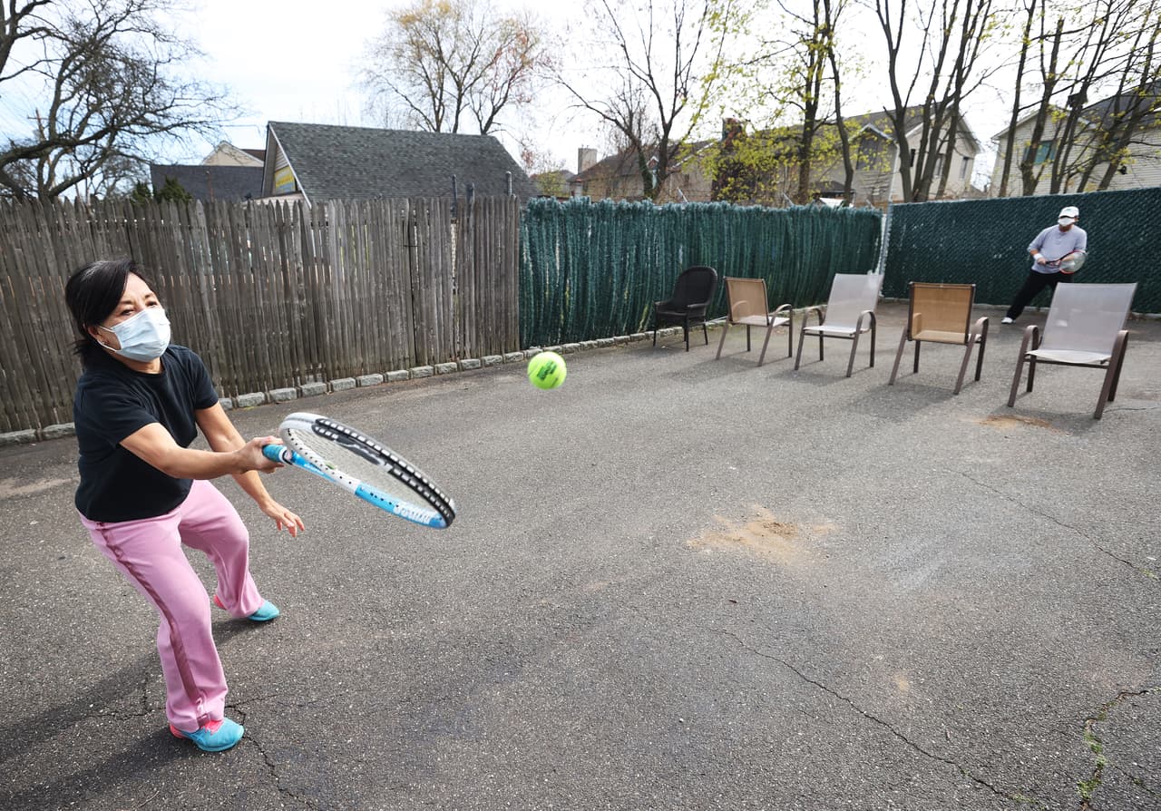 Una enfermera y su esposo juegan tenis en una cancha improvisada que montaron en su hogar en Merrick, New York. Las canchas de tenis han estado cerradas durante la "pausa".