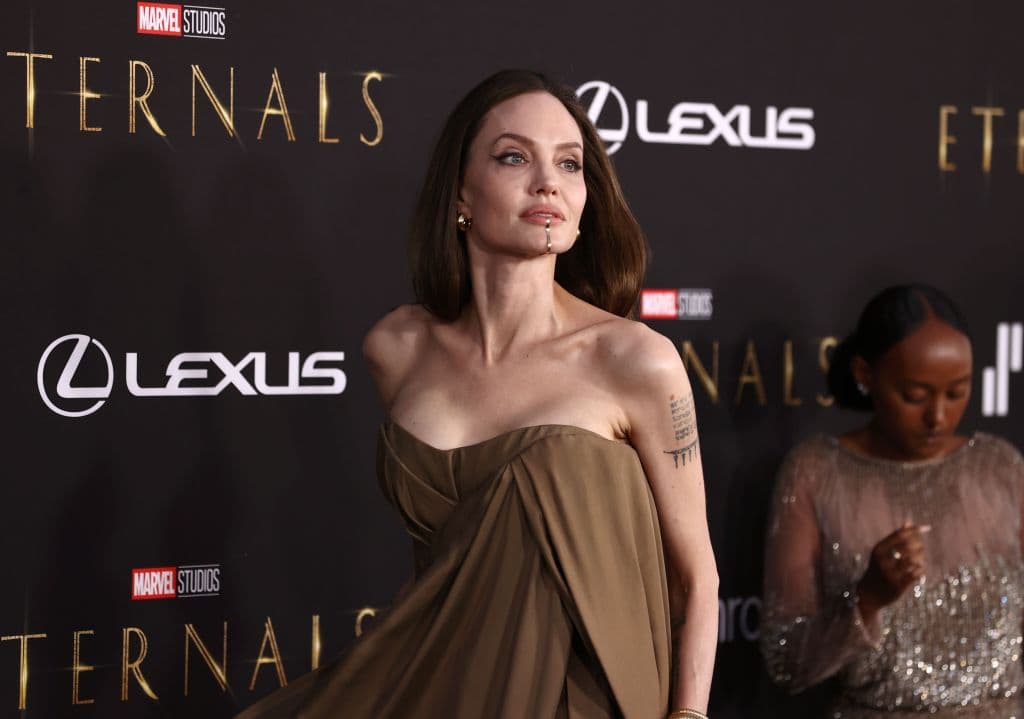 Angelina lució un vestido color oliva sin tirantes que combinó con pulseras de cadenas, pero un elemento destacado de su atuendo fue el accesorio de metal que bajaba de sus labios a la barbilla. 
<br>