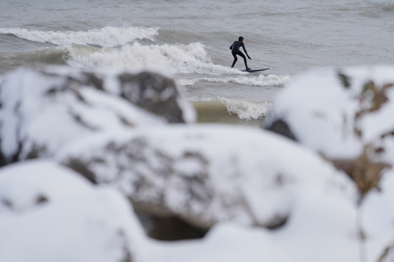 Hay quienes, ni la nieve, ni el frío les intimida para hacer sus actividades favoritas. Aquí un surfista aprovecha las olas durante el paso del frente ártico en Evanston.