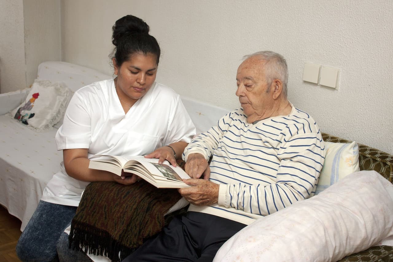 A nurse holds a book for an older adult.